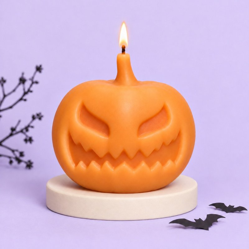 Vela naranja encendida con forma de calabaza malvada sobre una base y fondo lila