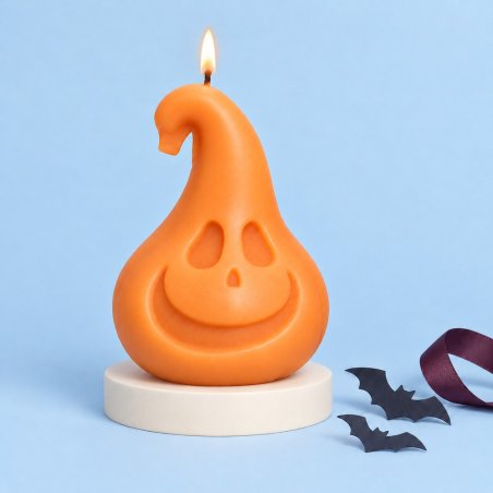 Vela naranja encendida con forma de calabaza sonriente y tallo curvado sobre una base y fondo azul
