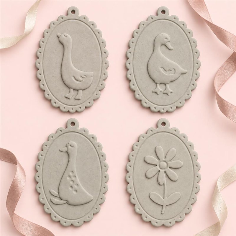 Quatre médaillons ovales beiges avec des oies et une fleur en relief sur fond rose