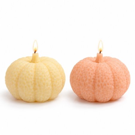 Deux bougies citrouilles rugueuses jaune et saumon allumées sur fond blanc