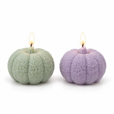 Dos velas de calabaza rugosa verde y lila encendidas sobre fondo blanco