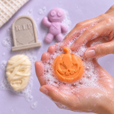 Mãos lavando-se com um sabonete de abóbora de Halloween e espuma