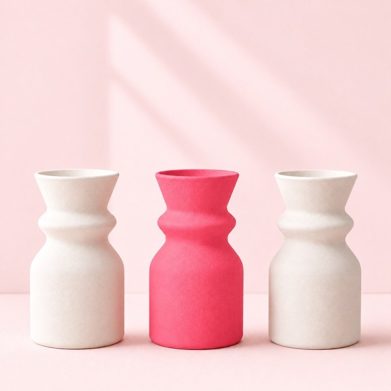 Vase rose chewing-gum entre deux vases blancs, exemple de plâtre coloré