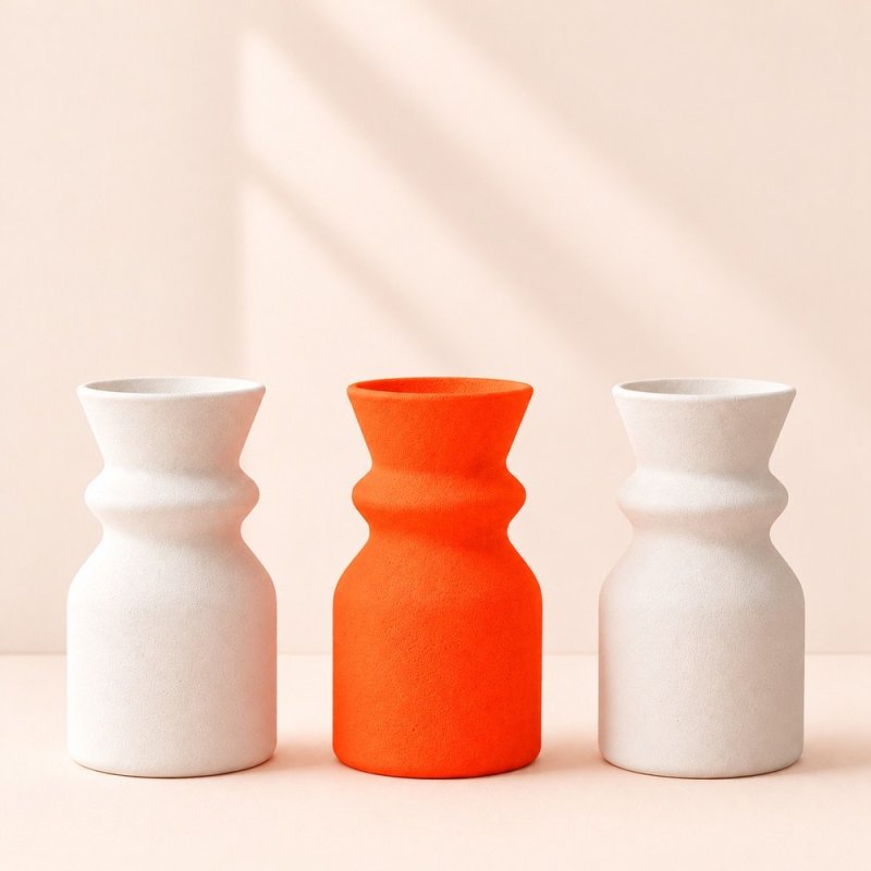 Vase orange néon entre deux vases blancs, exemple de plâtre coloré