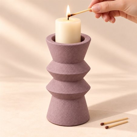 Mano encendiendo una vela en un portavelas lila de dos anillos