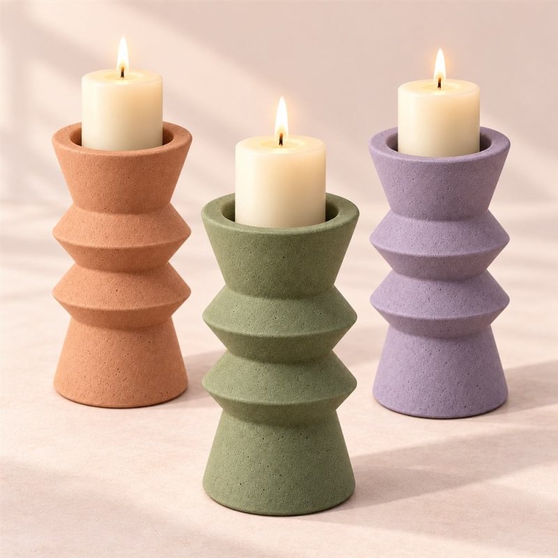 Três porta-velas geométricos de dois anéis em laranja, verde e lilás com velas