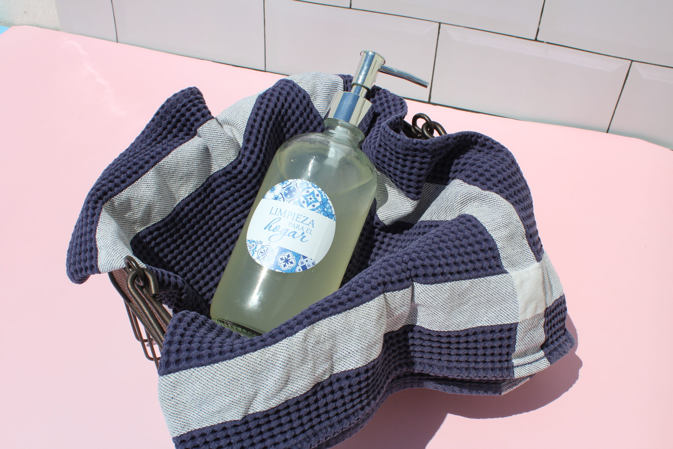 Botella de lavavajillas casero sobre un paño de cocina azul marino