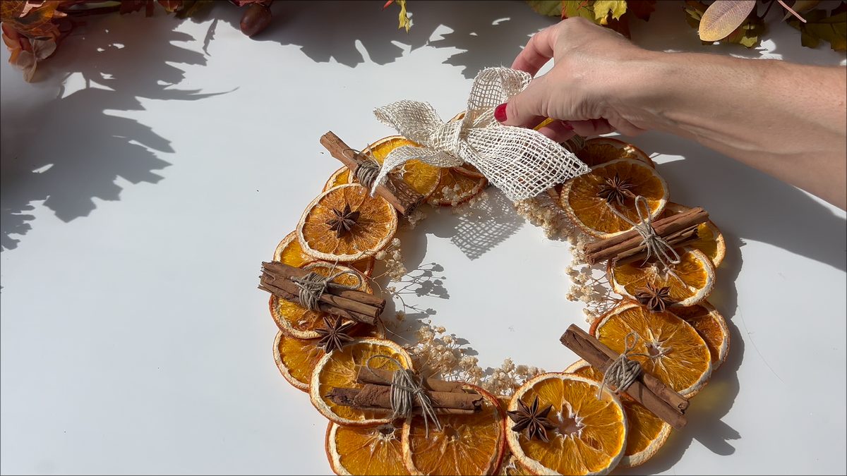 Colocando un lazo de cinta de yute blanca en la parte superior de la corona de otoño